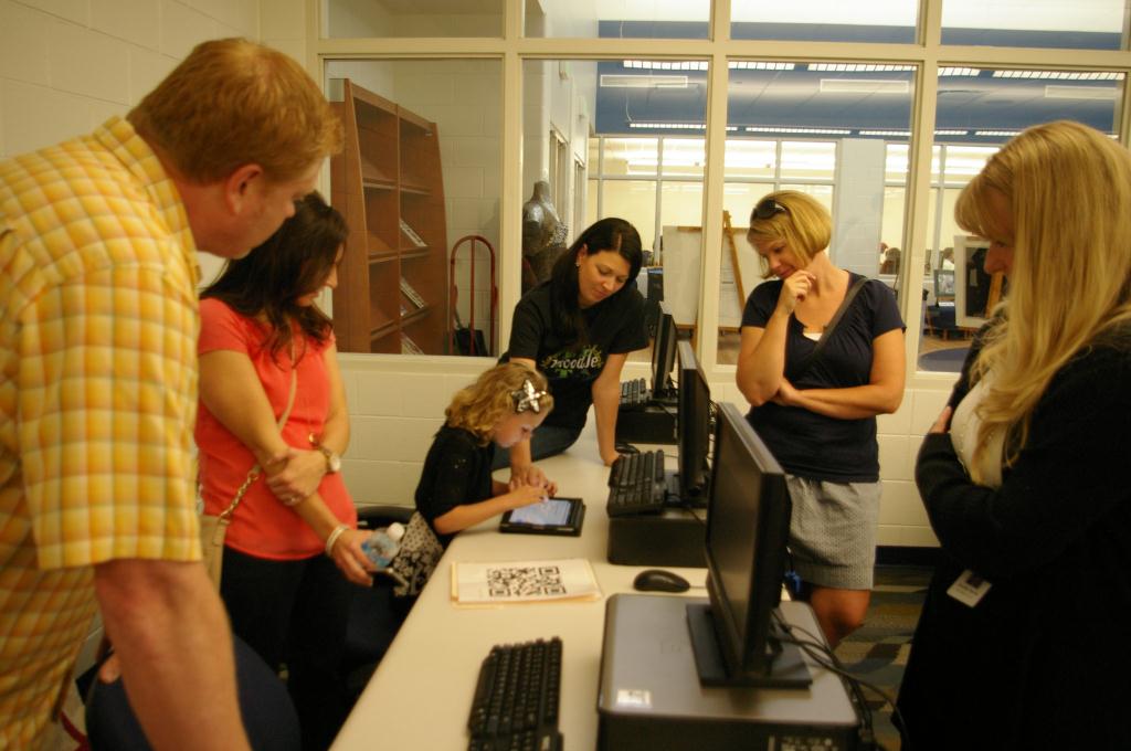 adults watching a child use a tablet in computer lab